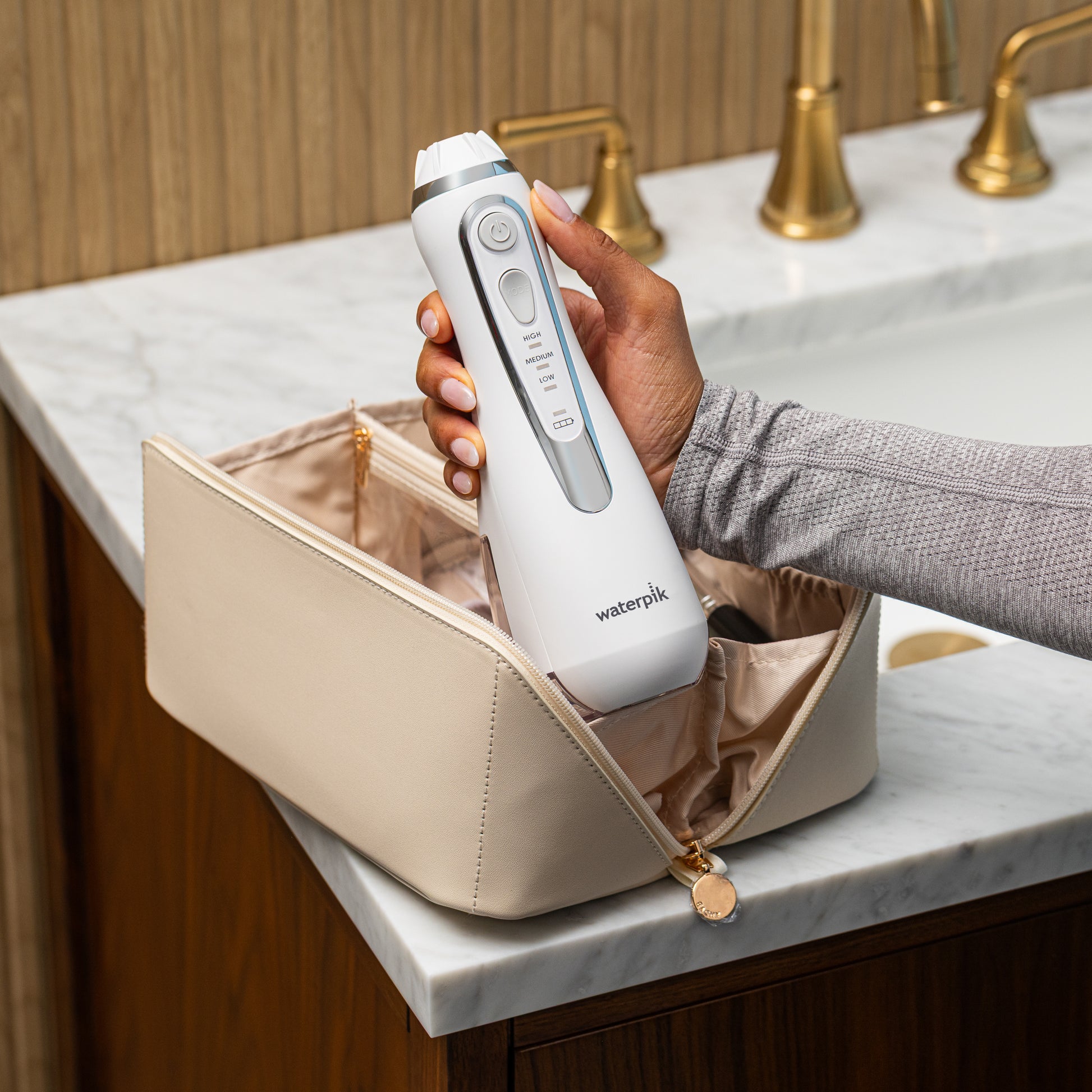 White Cordless Advanced 2.0 handheld water flosser, without tip, taken out of a toiletry bag.