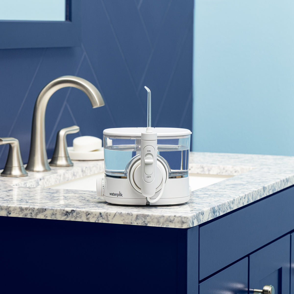 White ION countertop water flosser on a bathroom sink.